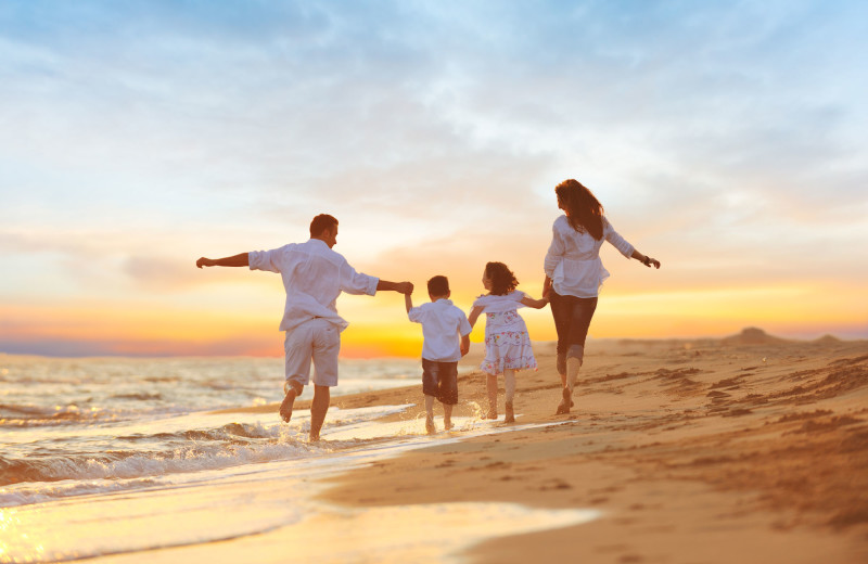 Family on beach at Barefoot Resort Rentals.