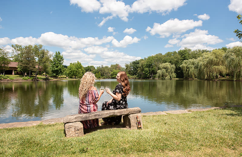 Two women sharing a laugh and a drink by the lake.