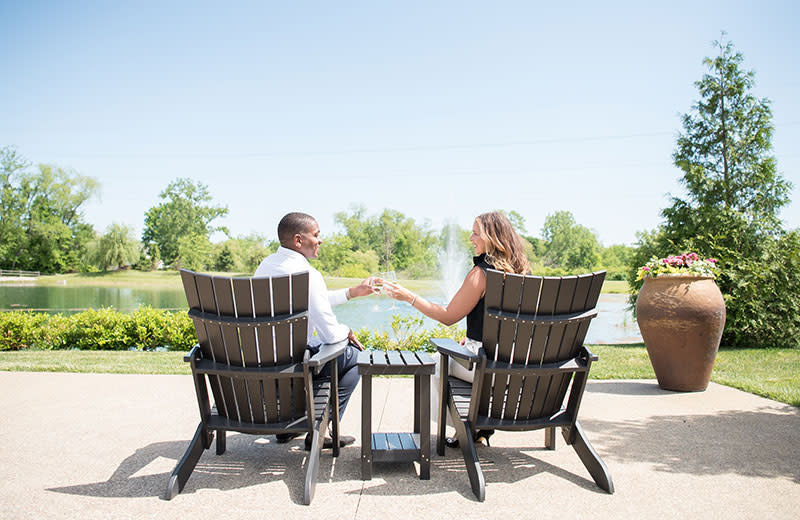 A young couple give cheers while sitting a the patio overlooking the lake.