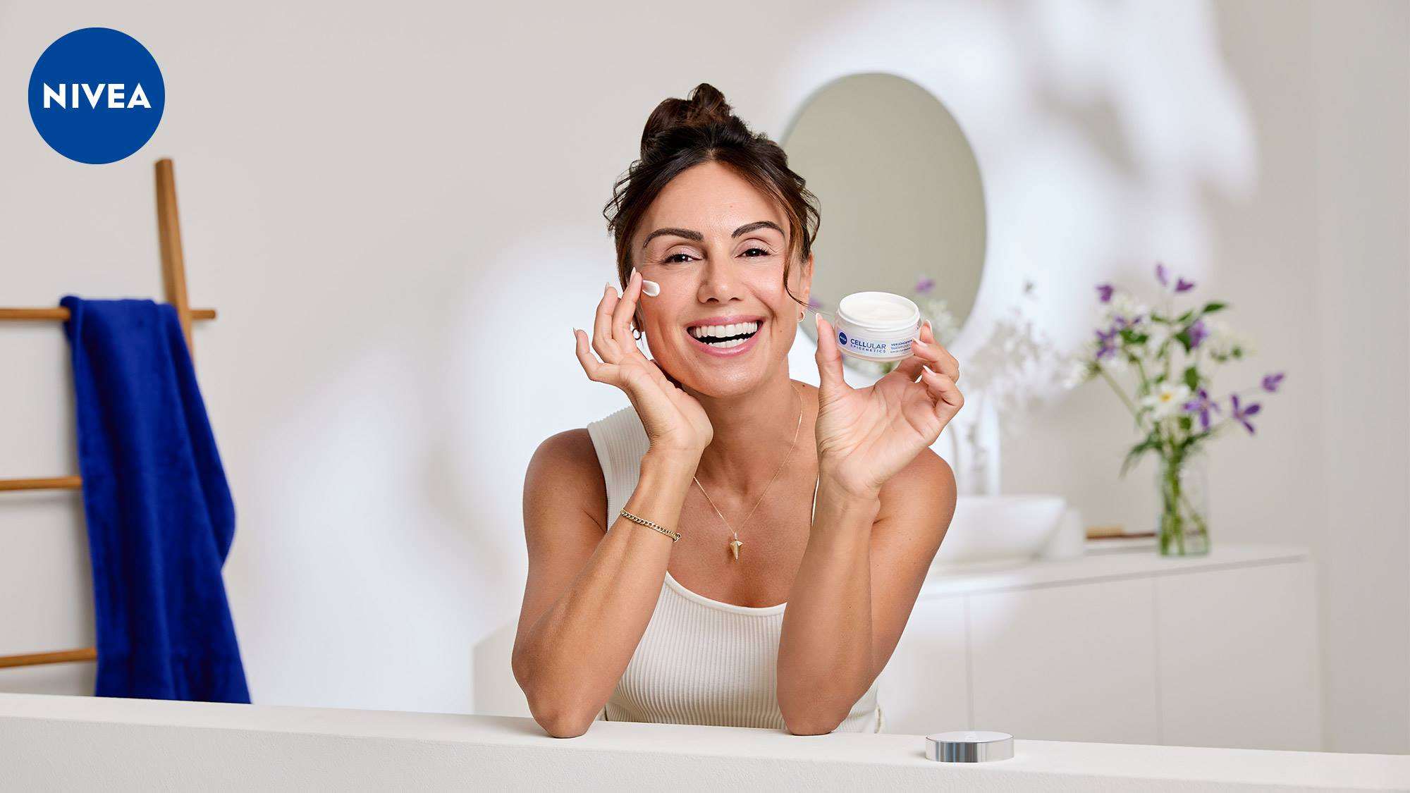 Frau trägt NIVEA Cellular Expert Gesichtspflege auf und hält den geöffneten Cremetiegel in der Hand