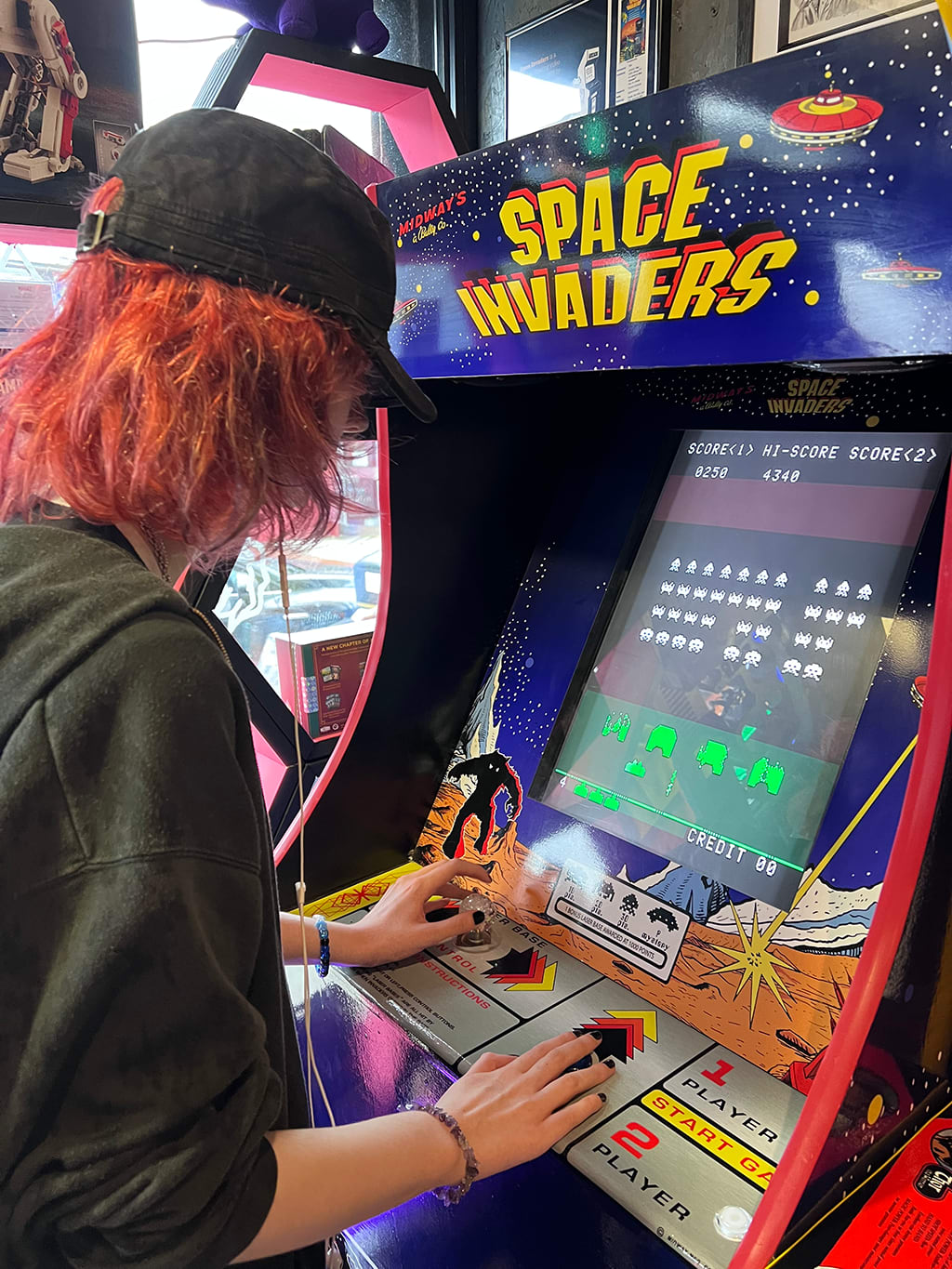 Alex Murray playing a space invaders arcade machine.