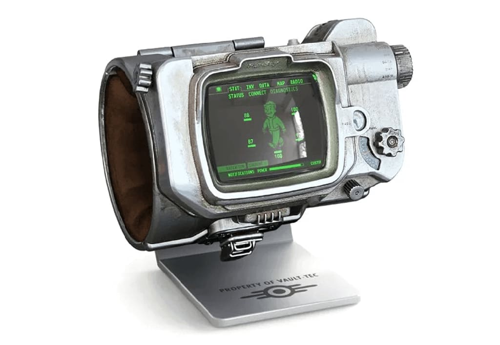 Pip-Boy A detailed replica of a Pip-Boy from the Fallout series, featuring a retro-futuristic design with a screen displaying a green monochrome interface. It is mounted on a stand labeled PROPERTY OF VAULT-TEC.