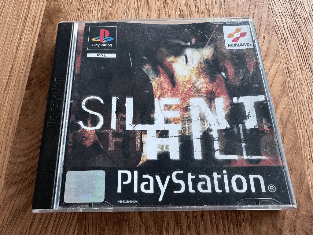 Silient Hill A copy of the Playstation 1 Silent Hill game in a case in a wooden table top.