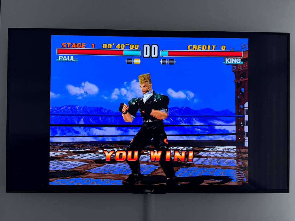 Tekken 3 A wall mounted Sony TV dispalying the Tekken 3 game with a character and the words 'You Win'.