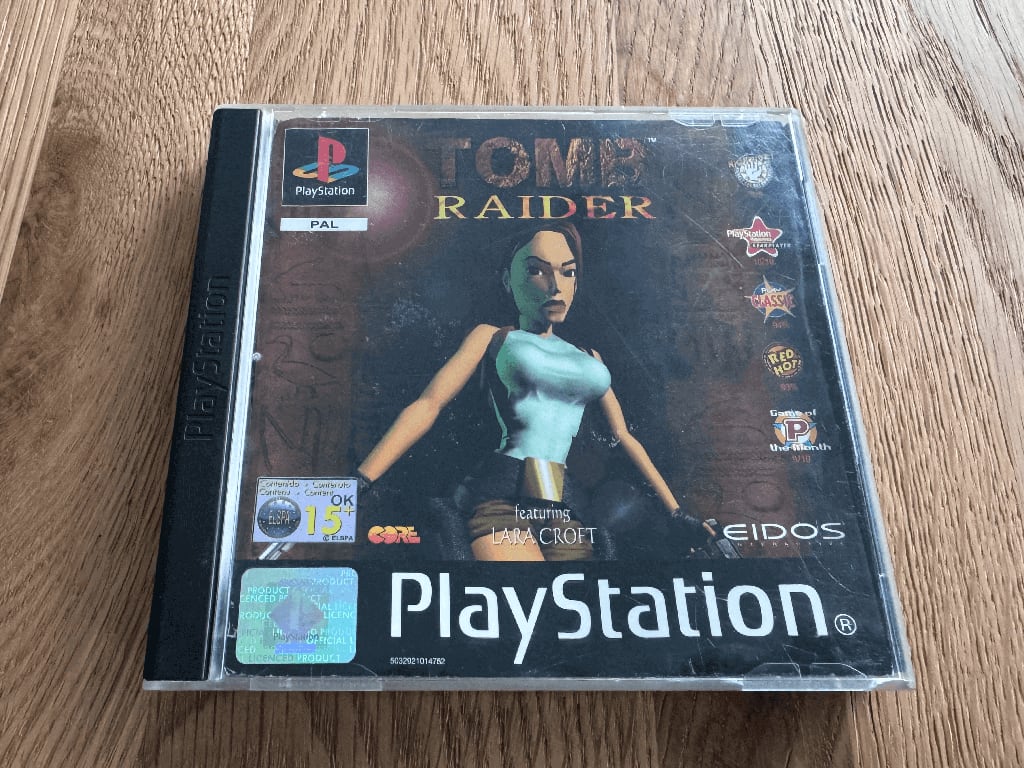 Tomb Raider A copy of the Playstation 1 Tomb Raider game in a case in a wooden table top