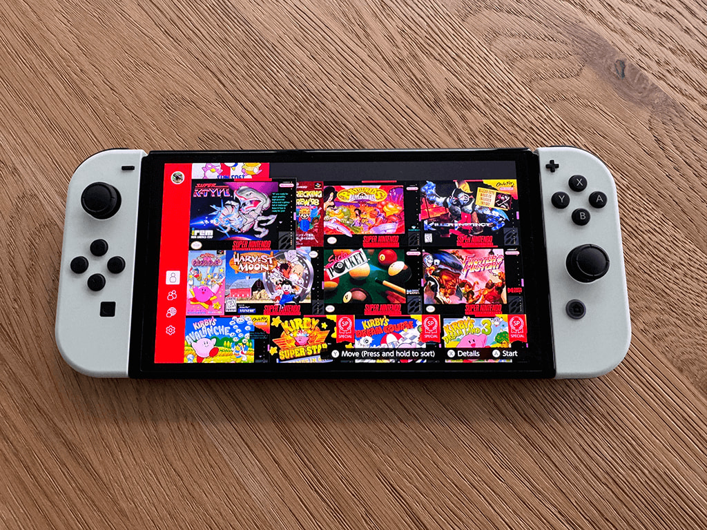 Nintendo OLED A Nitendo OLED Switch on a wooden surface displaying a selction of games from Nintendo Switch Online.