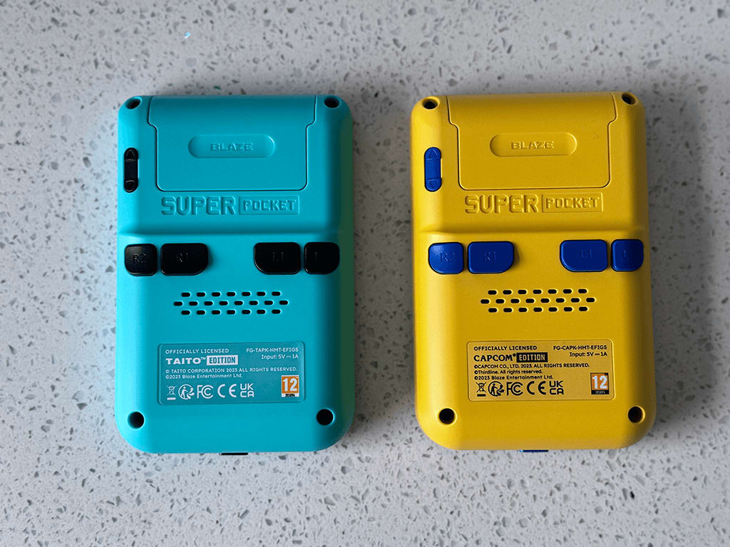 Super Pocket 3 The back of Taito and Capcom Super Pockets out of the packaging on a wooden table top.