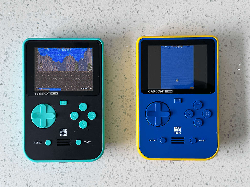 Super Pocket 5 The front of Taito and Capcom Super Pockets running 1942 and Rastan on a wooden table top.