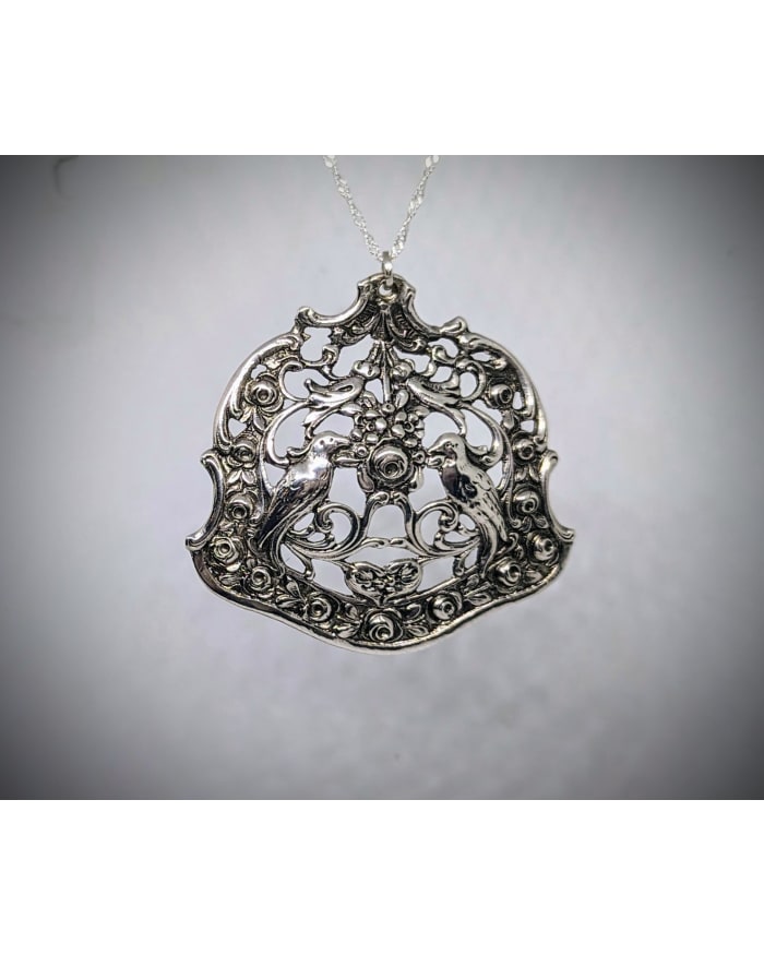 a silver pendant with birds on it