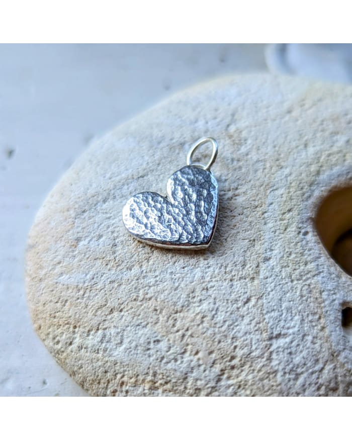 a heart shaped pendant on a rock
