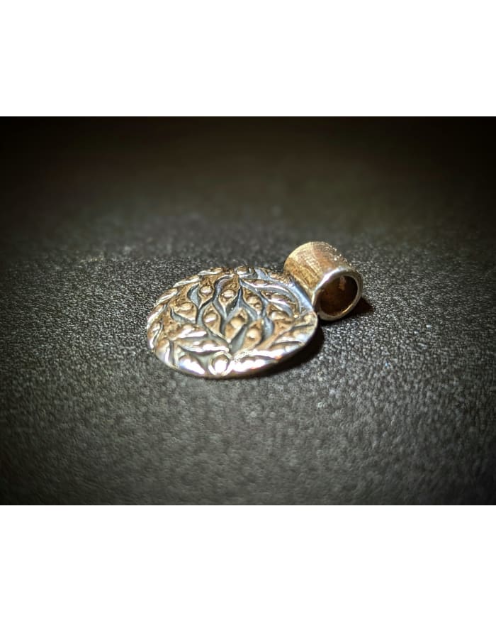 a silver pendant with a leaf design on it