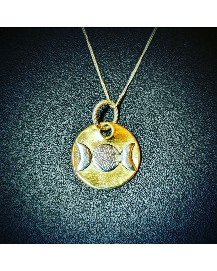 a gold pendant with a symbol on it