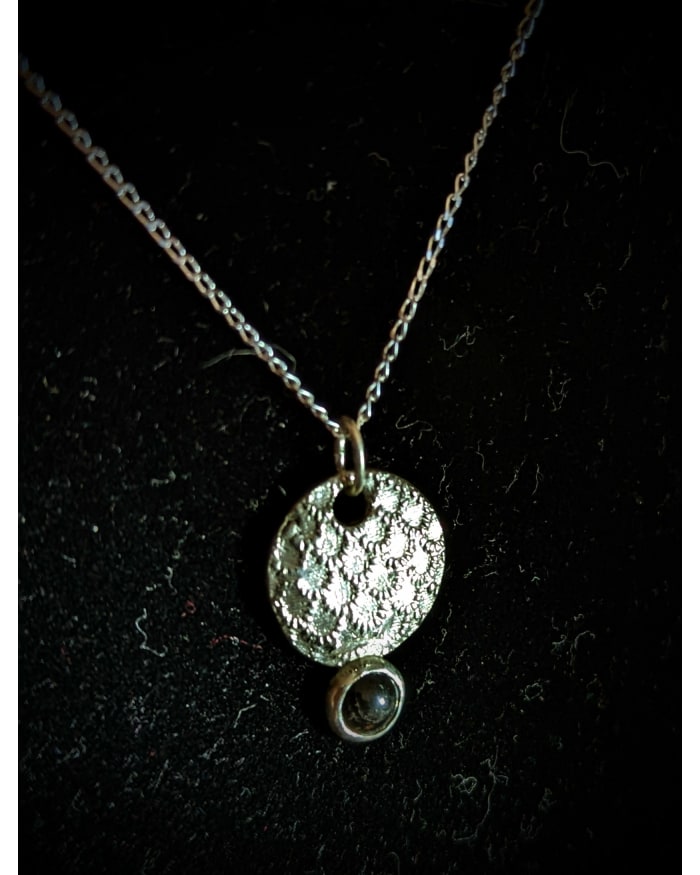 a silver necklace with a round pendant