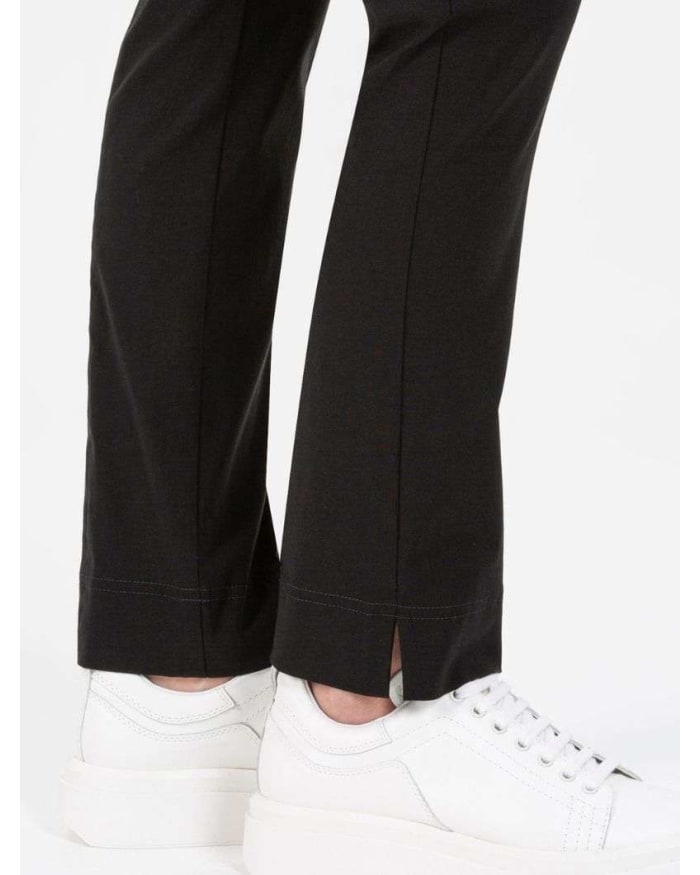 a person's legs in black pants and white shoes