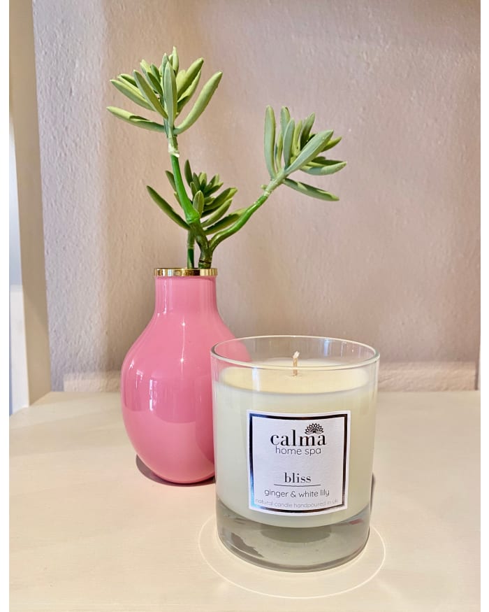 a candle and a plant in a pink vase