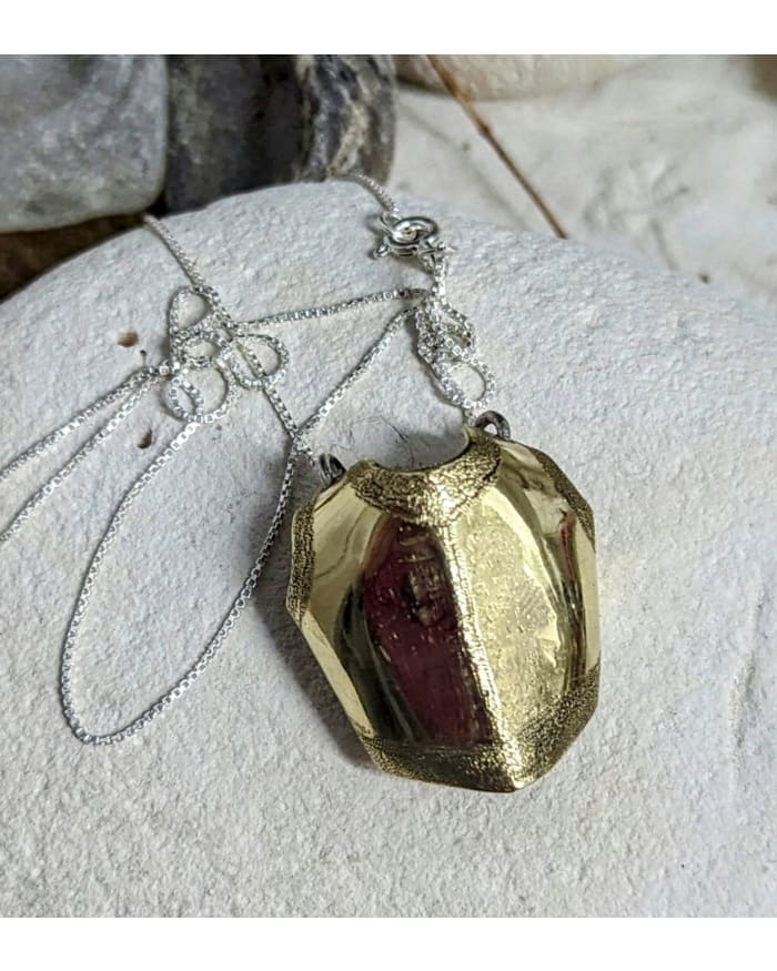 a gold necklace on a white stone