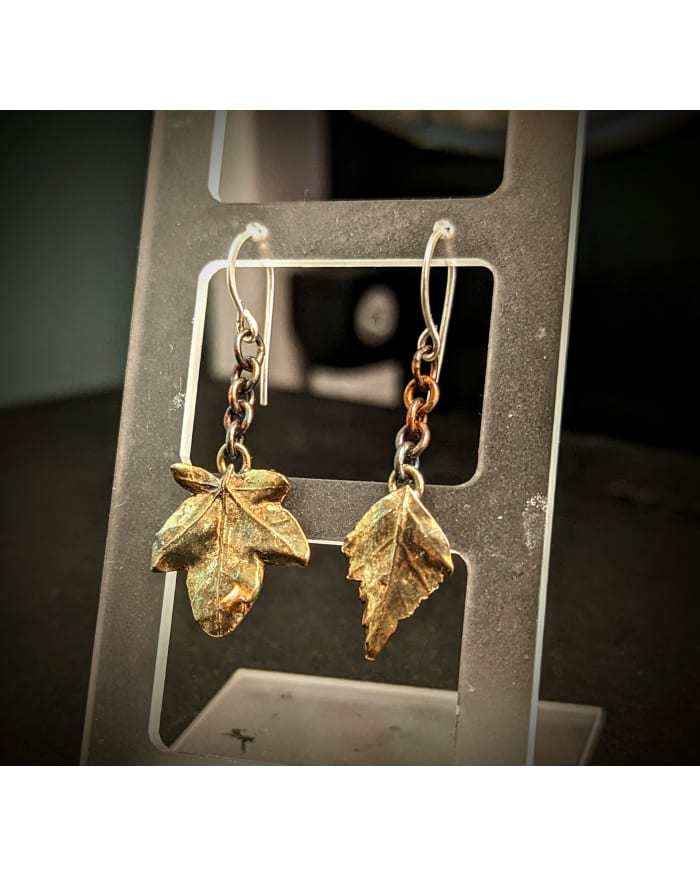 a pair of earrings with gold leaves