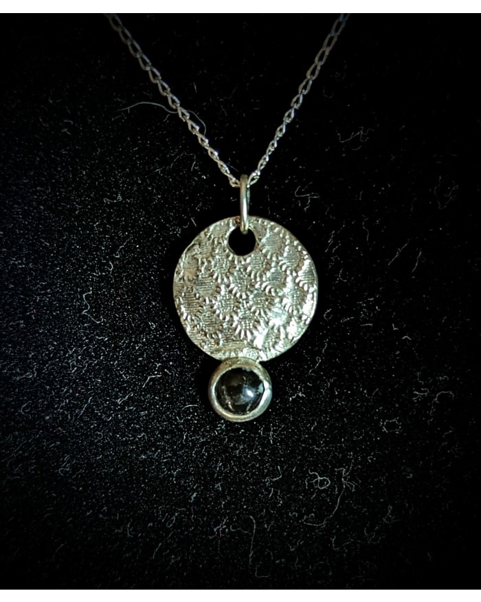 a silver necklace with a round pendant and a black stone