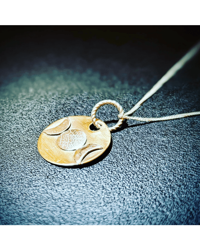 a gold medallion with a white design on a string