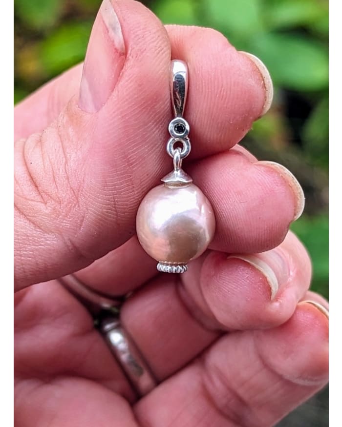 a hand holding a pearl pendant