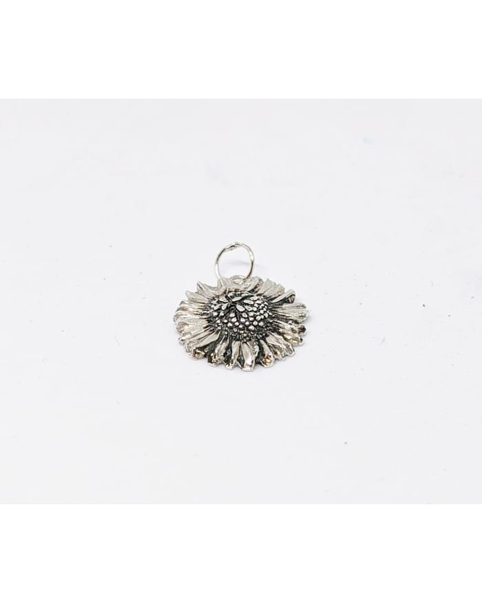 a silver flower pendant on a white surface