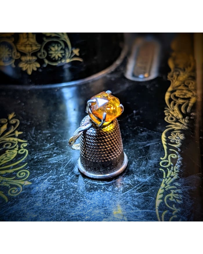 a thimble with a yellow gem on it