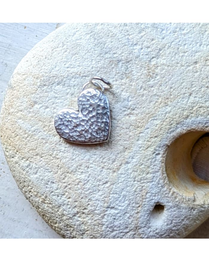 a heart shaped pendant on a rock