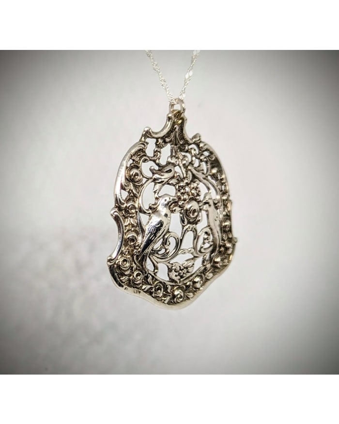 a silver pendant with a bird on it