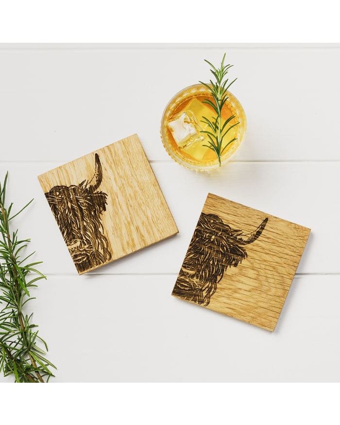 a drink with a branch of rosemary and a wooden coaster