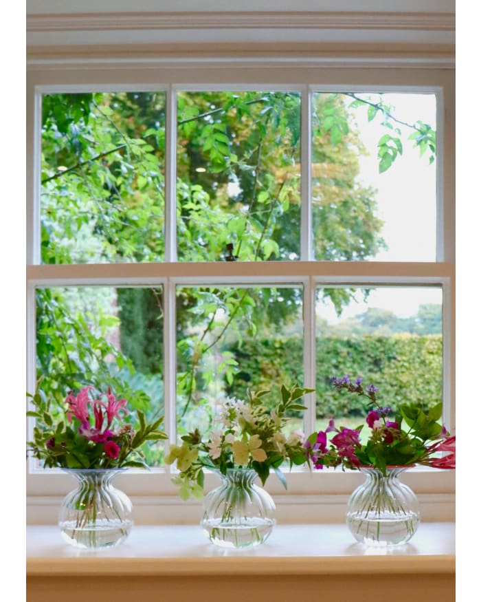 a group of vases of flowers in front of a window