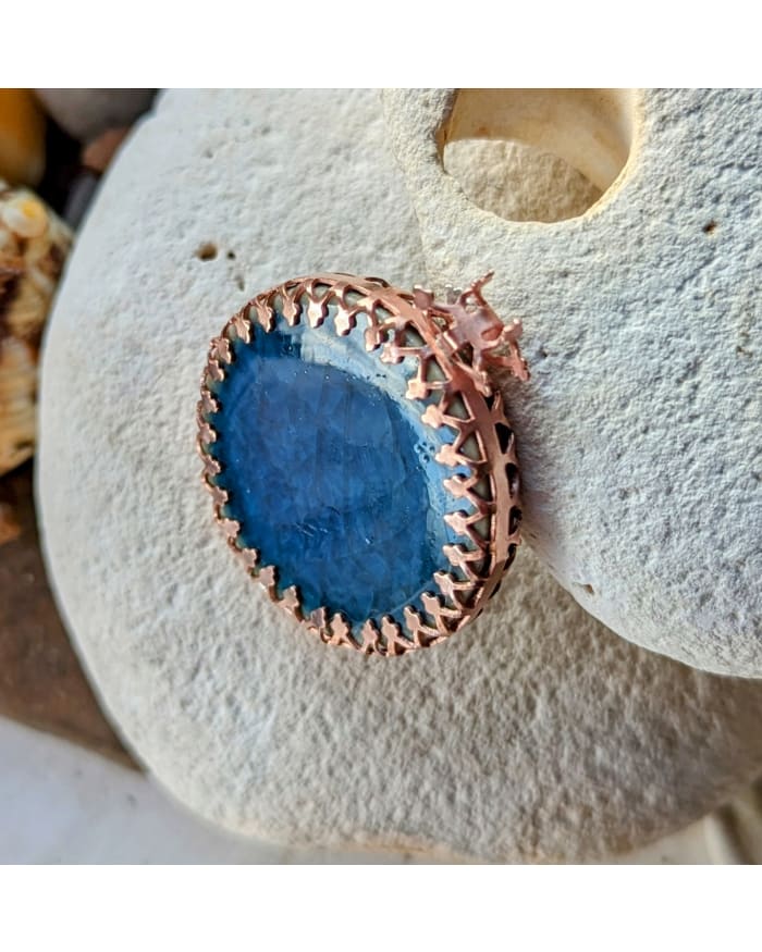 a blue stone with a gold border on a rock