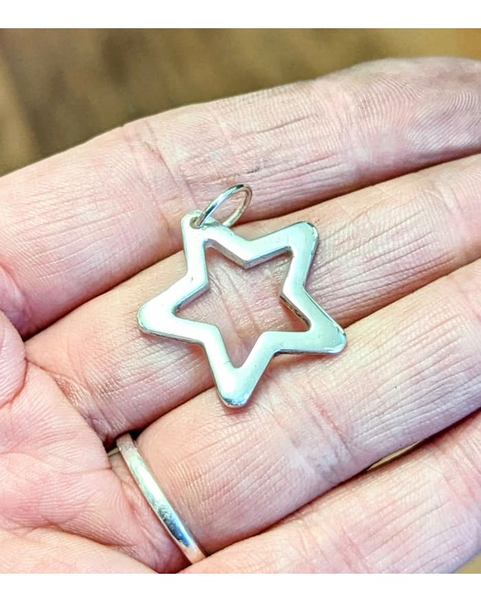 a hand holding a silver star pendant