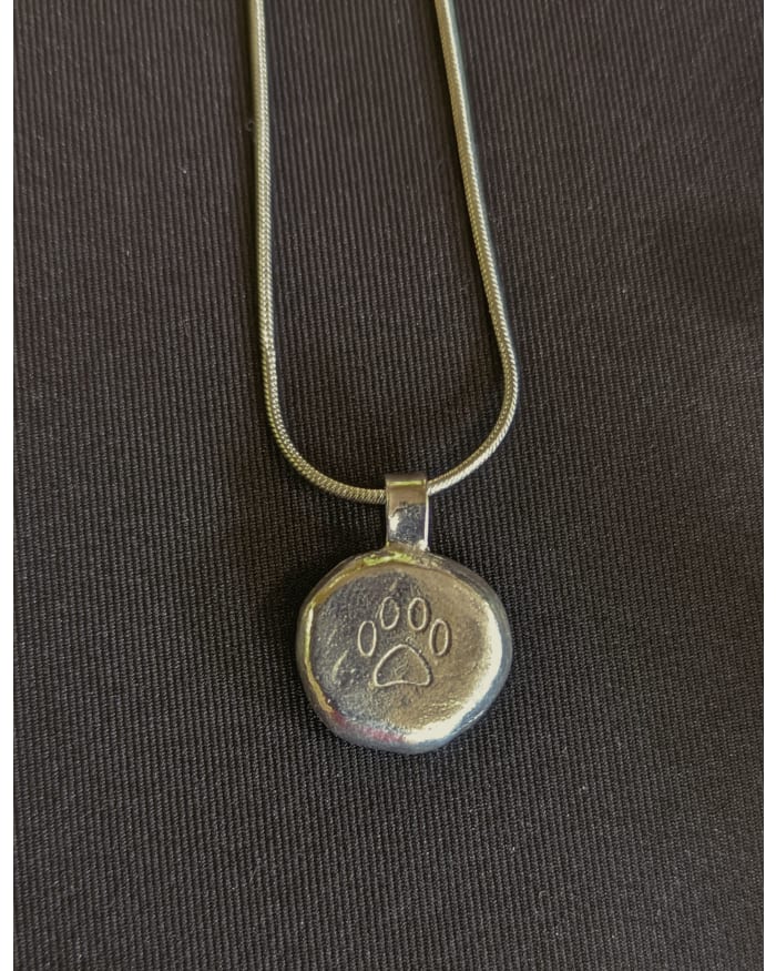 a silver pendant with a paw print on it