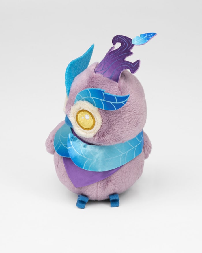 a purple stuffed animal with blue feathers and blue scarf
