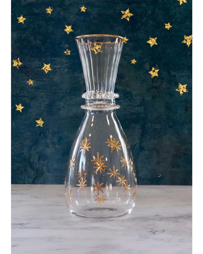 a glass vase with gold stars on a blue background