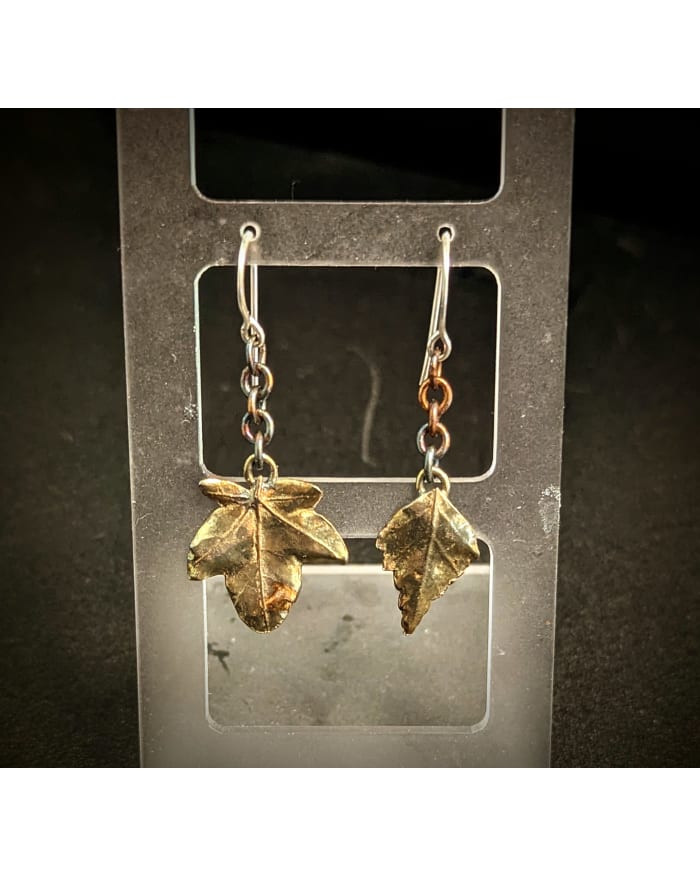 a pair of earrings with gold leaves