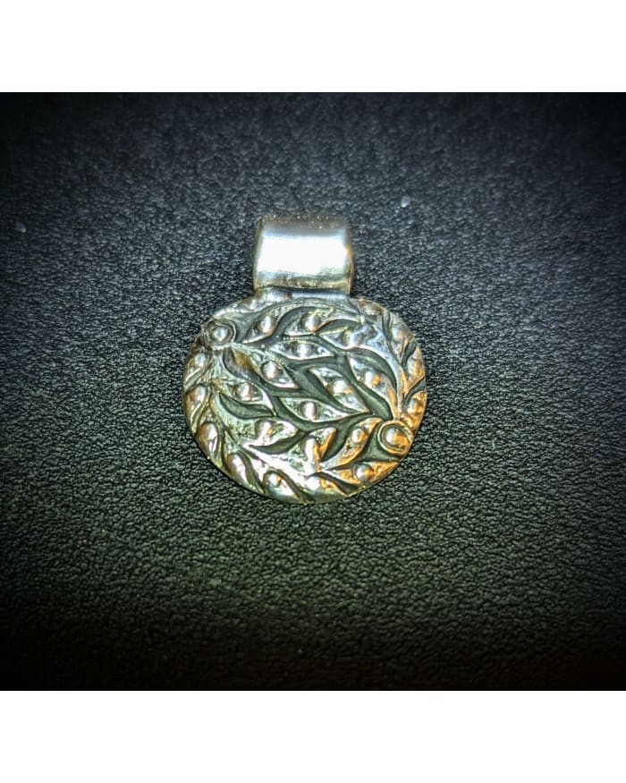 a silver pendant on a black surface