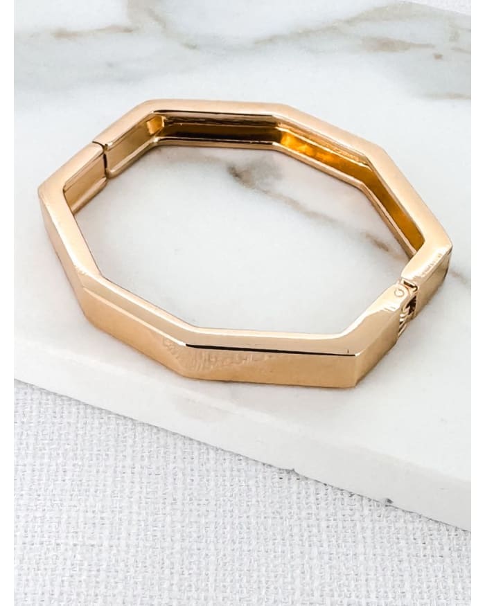 a gold bracelet on a white surface