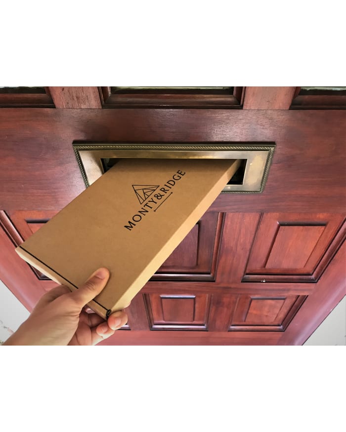 a hand holding a box in a mail slot