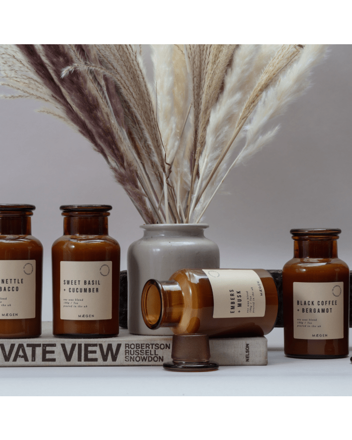 a group of brown bottles with white labels and a vase of dried flowers