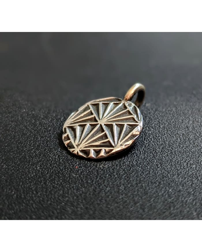 a silver pendant with a design on it