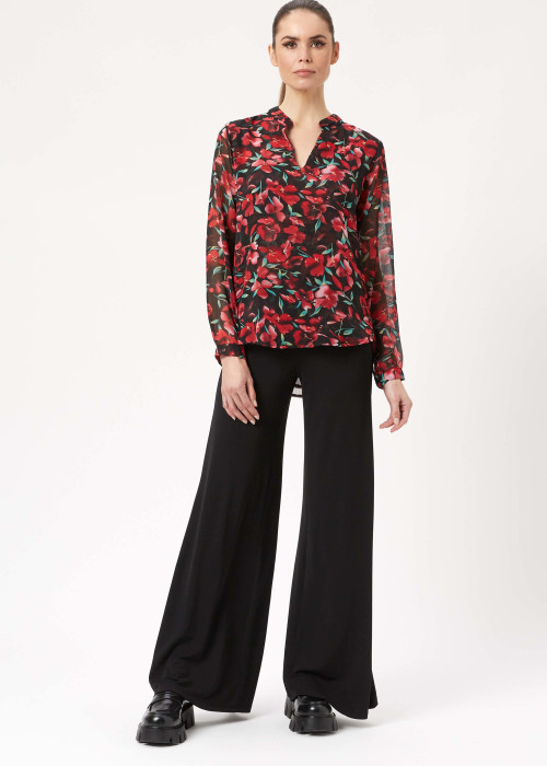 a woman wearing a floral shirt and black pants