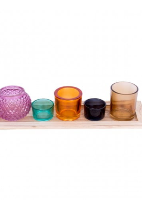 a group of colorful glass candlesticks on a wooden tray