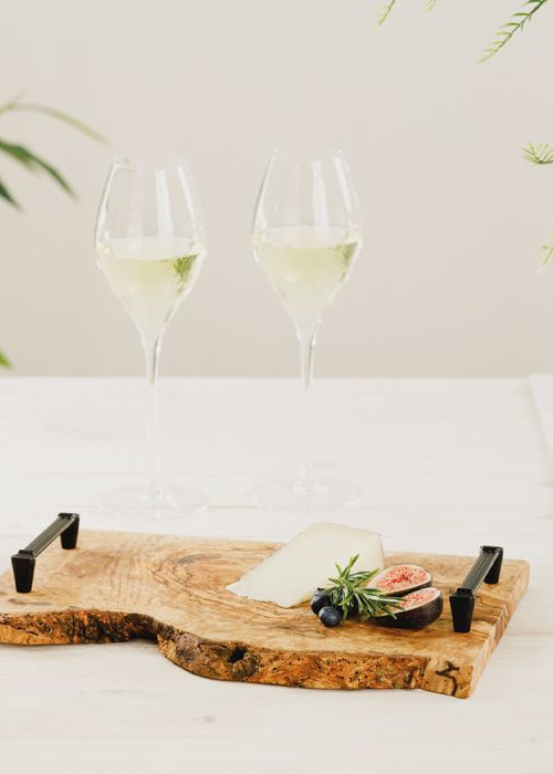 a wooden board with a cheese and a couple glasses of wine