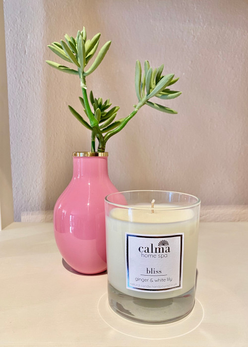 a candle and a plant in a pink vase