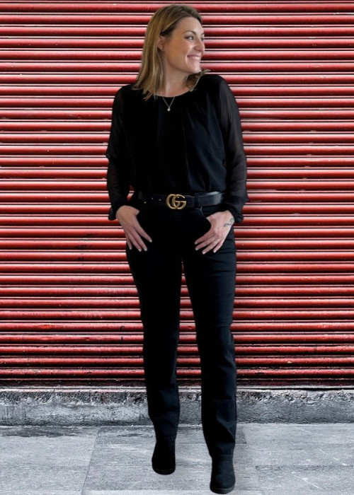 a woman in all black standing in front of a red garage door