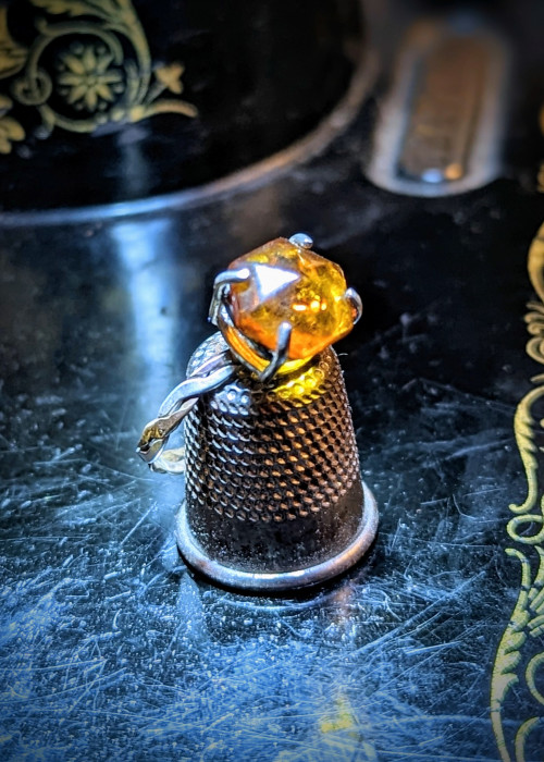 a thimble with a yellow gem on it