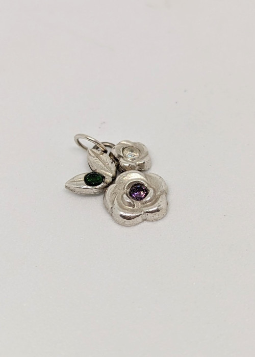 a silver flower with a green gem