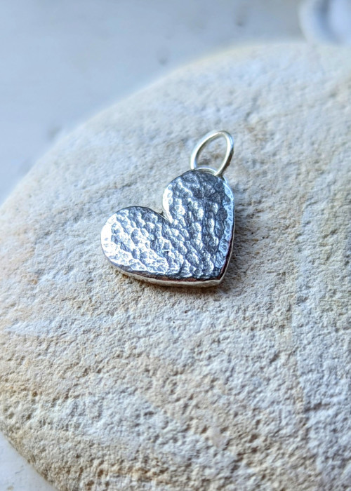 a heart shaped pendant on a rock