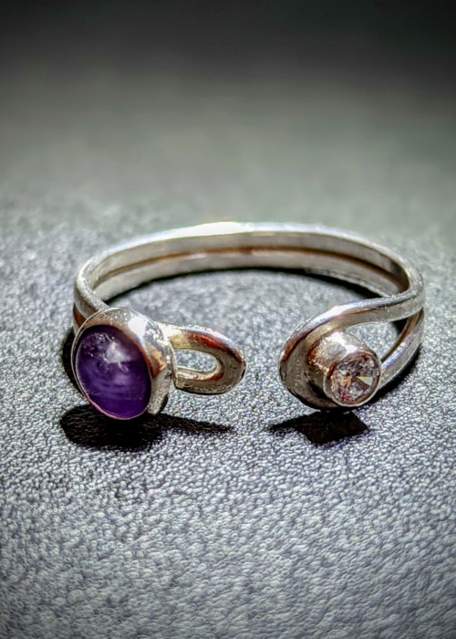 a silver ring with a purple stone and a small diamond